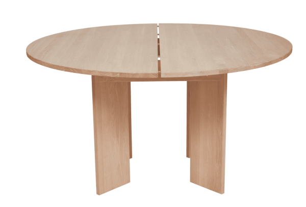 Et rundt OYOY - Kotai Spisebord Ø140 bord med split i midten på grøn baggrund. bordet har to ben forbundet i en t-form, hvilket indikerer et enkelt, minimalistisk design.
