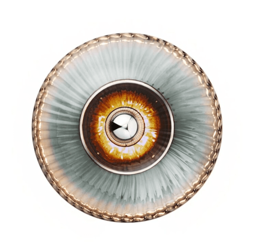 Dekorativ tallerken med et cirkulært design med en detaljeret, øjenlignende illustration i midten, omgivet af udstrålende aqua- og crememønstre med en struktureret kant.