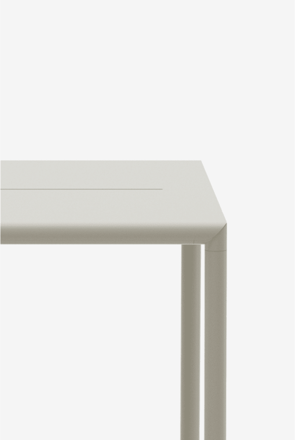 Nærbillede af et moderne hvidt bord fra TomorrowsDesign mod en almindelig baggrund med fokus på bordets rene linjer og retvinklede, glatte kryds, hvor bordpladen møder benet.