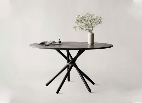 En minimalistisk indstilling med en EBERHART - Hector Spisebord 140 med en unik, stjerneformet base. På bordet står en keramikvase med hvide blomster og et lille, foldet gråt stof pænt placeret.