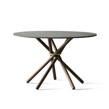 Et moderne rundt bord med en mørkegrå plade og en indviklet bund bestående af flere vinklede træben flettet sammen. Baggrunden er almindelig hvid, hvilket understreger bordets designmøbler.
