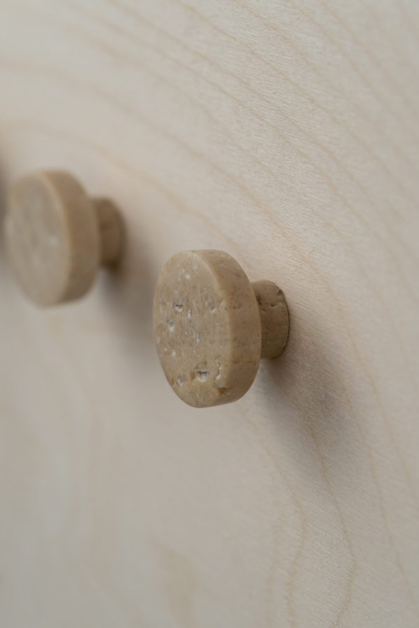 Nærbillede af to runde WABI SABI NORDIC - Musling Knage skabsknopper monteret på en let træoverflade, med fokus på materialets tekstur og naturlige mønster.
