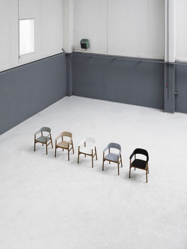 Fem stole med moderne design fra TomorrowsDesign i hver sin farve, placeret på række i et rummeligt rum i industriel stil med grå vægge og betongulv.