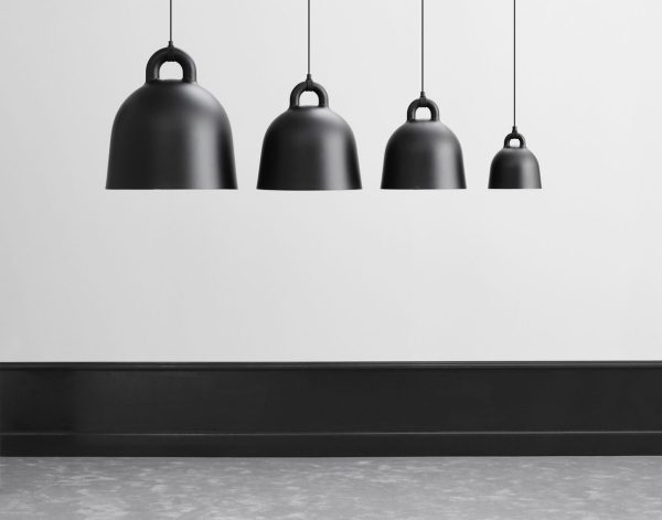 Tre NORMANN COPENHAGEN - Bell Lampe Ø55 pendellamper i forskellige størrelser, der hænger i forskellige højder i et rum med gråt gulv og hvid væg, der viser en minimalistisk indretning.