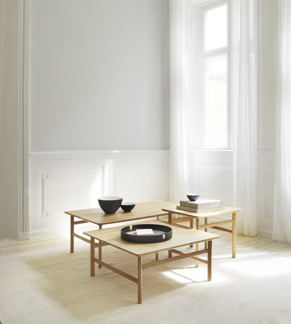 En minimalistisk stue med to indlejringsborde af træ med sorte skåle, sat på et tekstureret hvidt tæppe fra TomorrowsDesign på baggrund af lyse vinduer og hvide vægge.