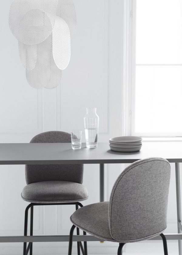 En minimalistisk spiseplads med to grå polstrede stole ved et elegant sort bord, sat mod en hvid baggrund med et stort vindue og en NORMANN COPENHAGEN Superpose Lampe ovenover.