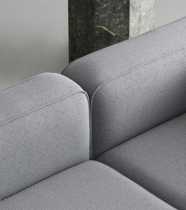 Et nærbillede af en Normann Copenhagen - Rope Modulsofa 120 Narrow Højre, der viser detaljeret tekstur, med en sløret baggrund med en delvis visning af en grøn marmorsøjle.