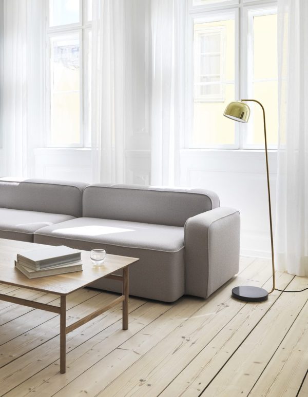 En minimalistisk stue med en stor NORMANN COPENHAGEN - Rope Modulsofa 120 Narrow Højre, et sofabord i træ med bøger, en stålampe og lyse vinduer med rene gardiner. rummet har hvide vægge og lyse trægulve.