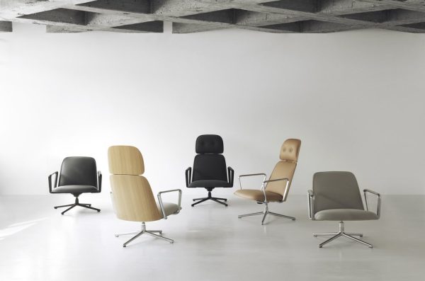 Fire NORMANN COPENHAGEN - Pad Lænestol stole med forskellige designs og farver, lige fra sort til beige, er pænt arrangeret på et betongulv i et minimalistisk hvidt rum med synlige loftsbjælker.