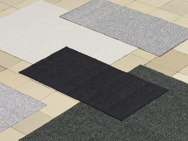 Fem NORMANN COPENHAGEN - Polli Gulvtæppe 200x300 af forskellige farver og teksturer vist på et flisegulv, set fra oven. tæpper inkluderer hvide, plettede grå, sorte og to nuancer af grøn.