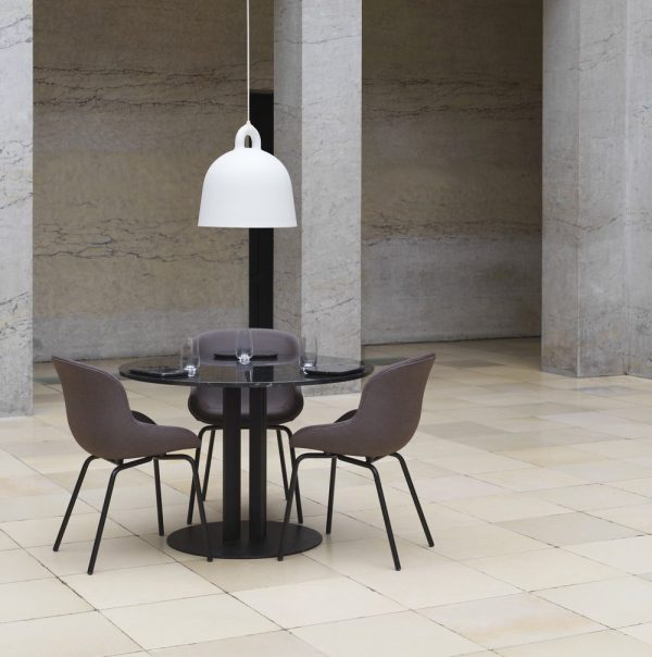 En moderne spisestue med et rundt glasbord og fire mørke stole i et rummeligt værelse med marmorsøjler og beige klinkegulv, oplyst af NORMANN COPENHAGEN - Bell Lampe Ø42.