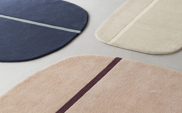 Fire NORMANN COPENHAGEN - Oona Gulvtæppe 140x140 bademåtter i bløde neutrale og mørke marinefarver, hver prydet med et enkelt linjedesign, arrangeret på en enkel grå baggrund.