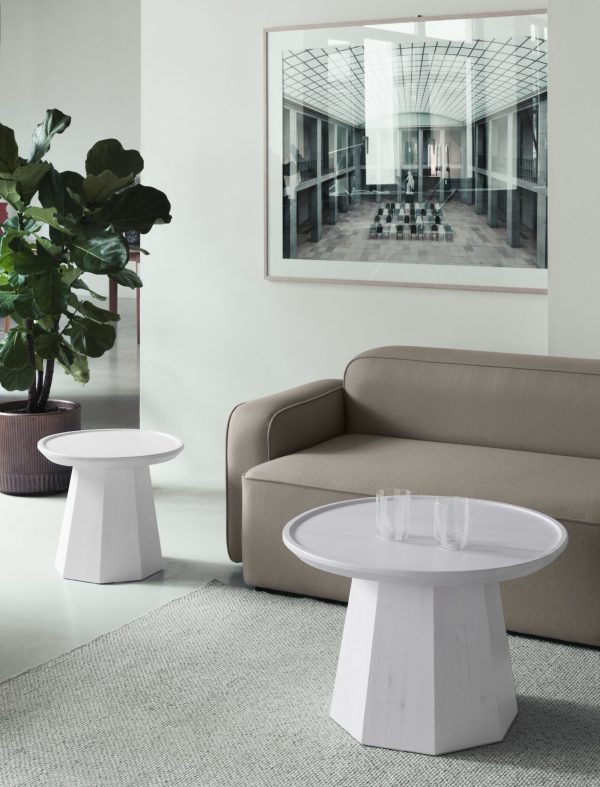 En fredfyldt, moderne stue med en NORMANN COPENHAGEN - Pine Sofabord Ø45 sofa, to hvide svampeformede sofaborde og et stort indrammet fotografi af en rummelig lobby på væggen. En frodig grøn plante tilføjer et strejf af natur til det raffinerede design.