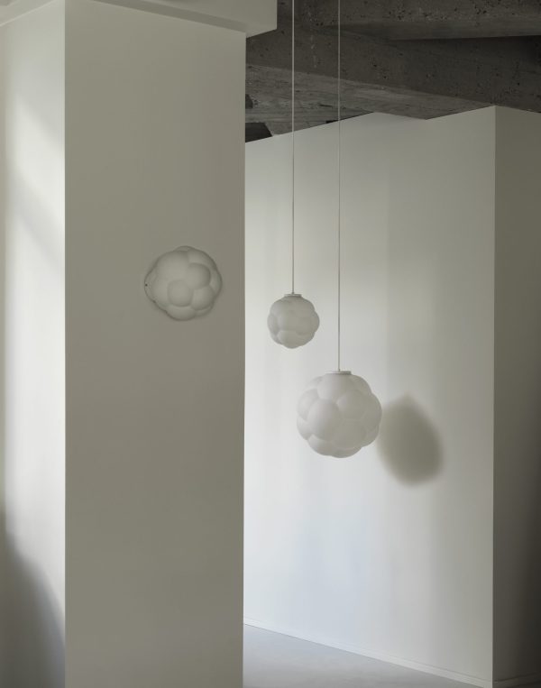 Tre NORMANN COPENHAGEN - Bubba Loftslampe Ø42 pendellamper med skylignende design hængende i forskellige højder i et minimalistisk interiør med beton og hvide vægge.