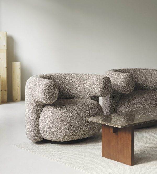 Et moderne, hyggeligt værelse med en NORMANN COPENHAGEN - Burra Loungestol M. Drejefunktion stol og matchende sofa ved siden af et elegant, mørkt marmor sofabord, alt sammen sat på et lys beige tæppe. enkle lyse træpaneler og grå vægge giver en minimalistisk kulisse.