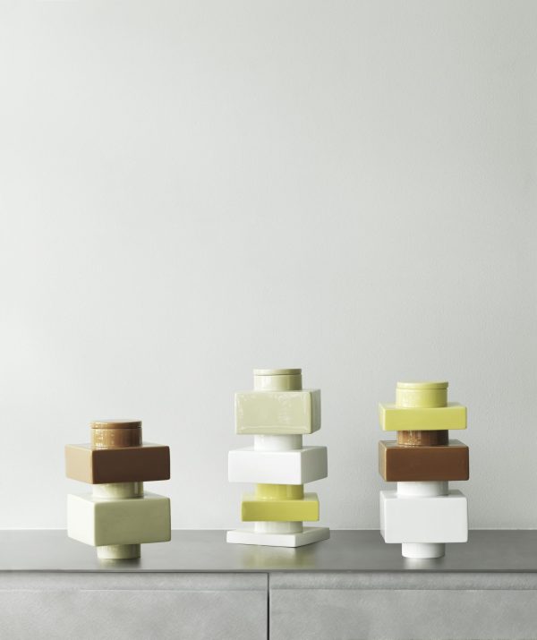 Tre stakke NORMANN COPENHAGEN - Deko Object S4 i cylindriske beholdere varierer i størrelse og farve, arrangeret på en lysegrå overflade mod en lysegrå baggrund.