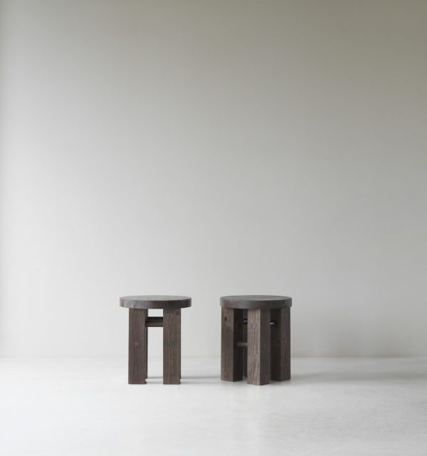 To NORMANN COPENHAGEN - Fyr Skammel taburetter står på et almindeligt hvidt gulv mod en lysegrå væg, placeret med et lille mellemrum mellem dem, og fremviser en minimalistisk indretning.