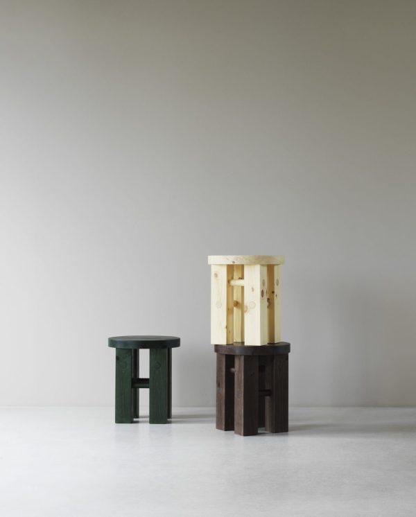 To NORMANN COPENHAGEN - Fyr Skammel træskamler i forskellige designs og farver, den ene mørkegrøn og den anden naturligt træ, placeret mod en almindelig lysegrå baggrund.