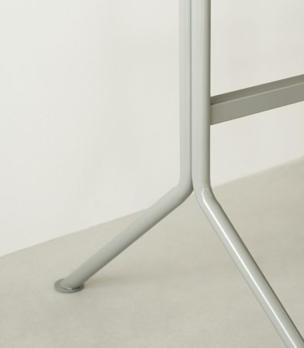 Nærbillede af den nederste del af et NORMANN COPENHAGEN - Kip Skrivebord ben på et lys beige gulv, der fremhæver det enkle design og krydset, hvor benet møder gulvet.
