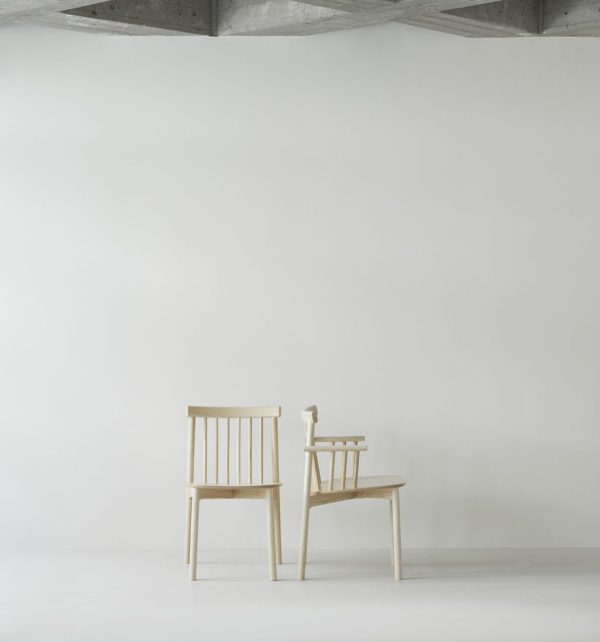 To træstole placeret side om side mod en almindelig hvid væg i et minimalistisk rum med et synligt betonloft, der viser TomorrowsDesign-æstetik.