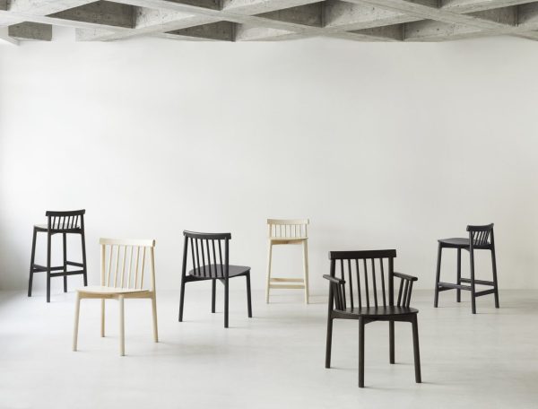 Fem stole i forskellige stilarter og farver, jævnt fordelt fra hinanden, placeret i et minimalistisk gråt rum med betonloft og hvide vægge, som eksemplificerer TomorrowsDesign-æstetik.