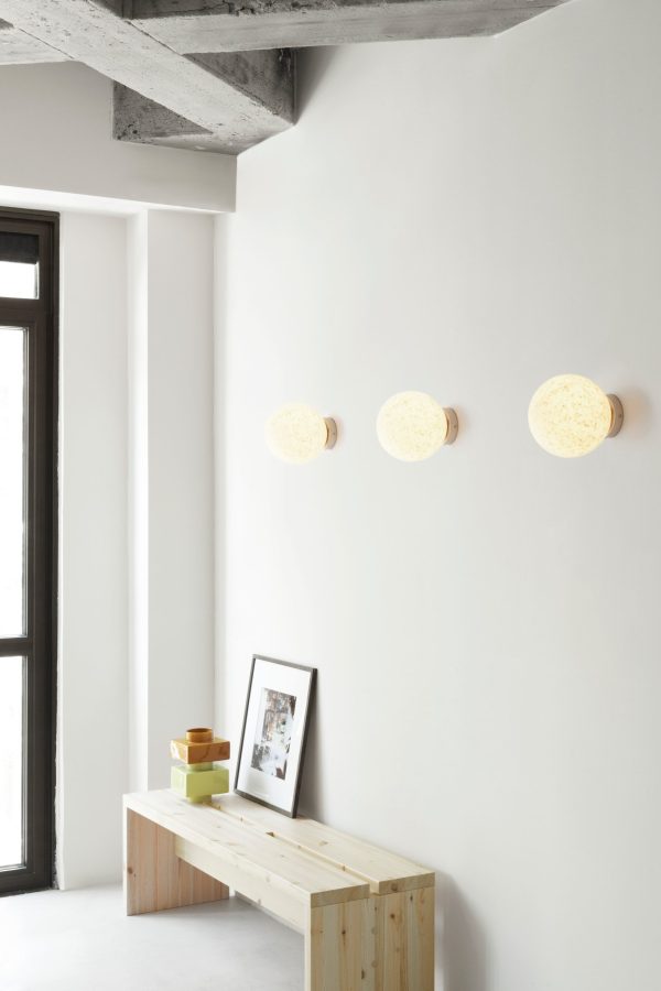 Moderne minimalistisk værelse med hvide vægge med tre NORMANN COPENHAGEN Pix Lampe Ø20 vægmonterede lamper. en træbænk med en fotoramme og dekorative genstande er placeret nær et vindue med sort ramme.