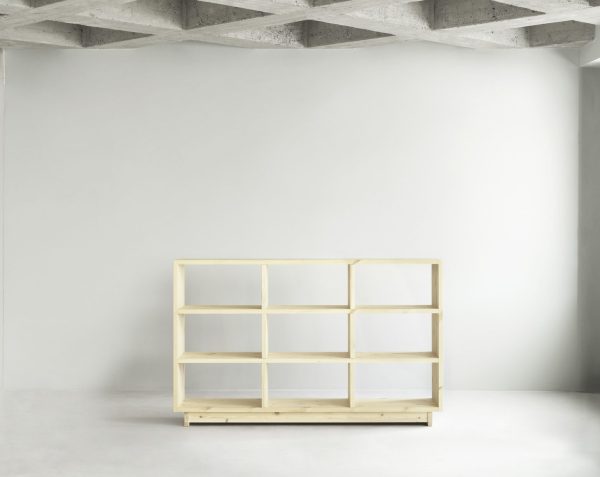 A NORMANN COPENHAGEN - Plank Bogreol Høj står i et betonrum med bar, hvid væg og fritlagte loftsbjælker. Hylden er tom og har flere rum af varierende størrelse.