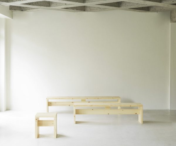 Et minimalistisk interiør med en almindelig hvid væg og betonloft med to NORMANN COPENHAGEN - Stretch Bænk 200 placeret på et lysegråt gulv.