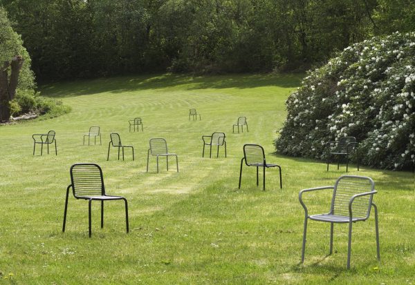 Flere NORMANN COPENHAGEN - Vig Havestol stole er spredt ud over en frodig, grøn græsplæne med pænt klippede striber. en stor busk med hvide blomster ses til højre. omgivelserne er rolige og solbeskinnede.