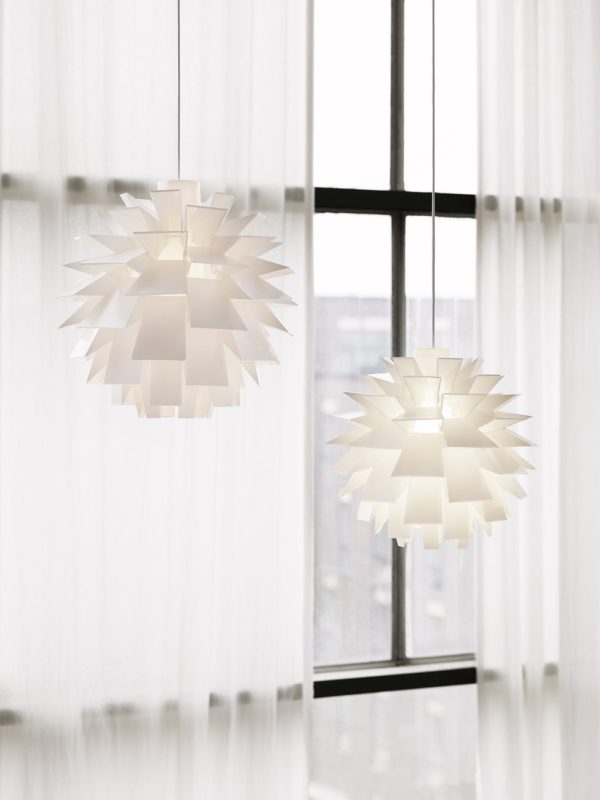 To NORMANN COPENHAGEN - Norm 69 Lampe XX-Stor med geometriske designs hængende foran et stort vindue med gennemsigtige gardiner. billedet er lyst, hvilket understreger rummets luftige og rene æstetik.