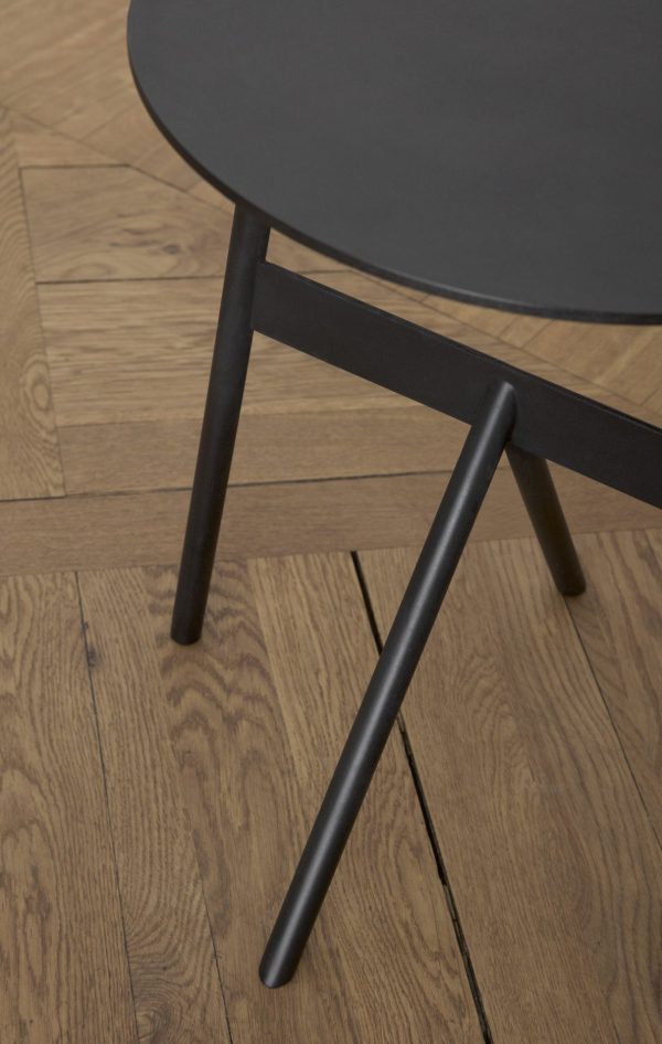 Nærbillede af et NORMANN COPENHAGEN - Stock Bord Ø37 bordben på et trægulv, der fremhæver teksturen og det enkle design af både bordet og gulvplankerne.