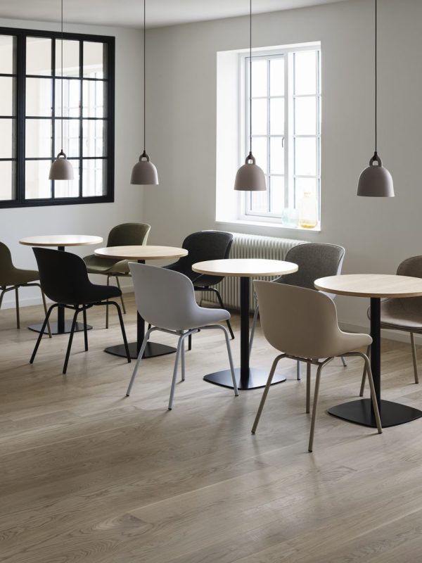 Moderne caféinteriør med minimalistisk design med flere runde og firkantede borde, en blanding af hvide og sorte stole fra TomorrowsDesign, pendelbelysning og store vinduer, der slipper naturligt lys ind.