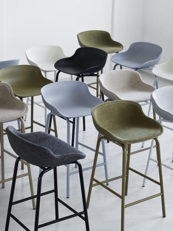 Forskellige moderne stole og barstole i dæmpede farver, arrangeret i et lyst hvidt rum. Designmøbler-stykkerne har et slankt design med en blanding af stof og metalmaterialer.