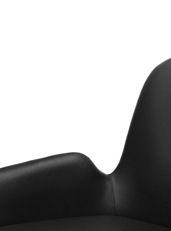 Nærbillede af en sort læderkontorstol med høj ryg, med fokus på den øverste venstre del af ryglænet mod en hvid baggrund, der viser dets slanke design.