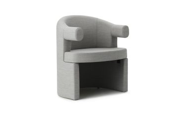 EN NORMANN COPENHAGEN - Burra Stol med et unikt, buet design på hvid baggrund. stolen har en glat stoffinish og er stylet med cylindriske armlæn.