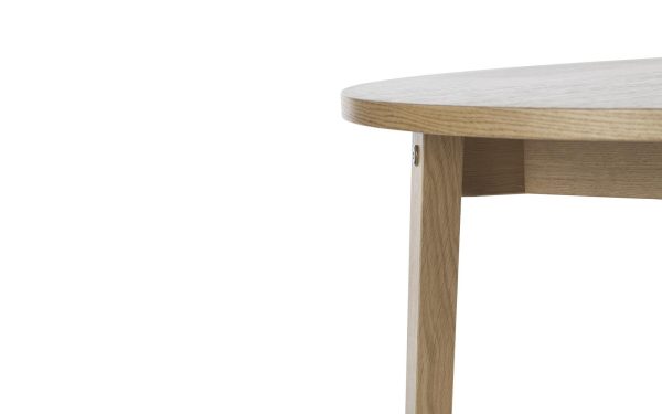 Nærbillede af hjørnet af et lyst træbord fra TomorrowsDesign, der viser detaljer om dets glatte overflade og samlingen, hvor bordpladen forbinder til benet, sat mod en hvid baggrund.