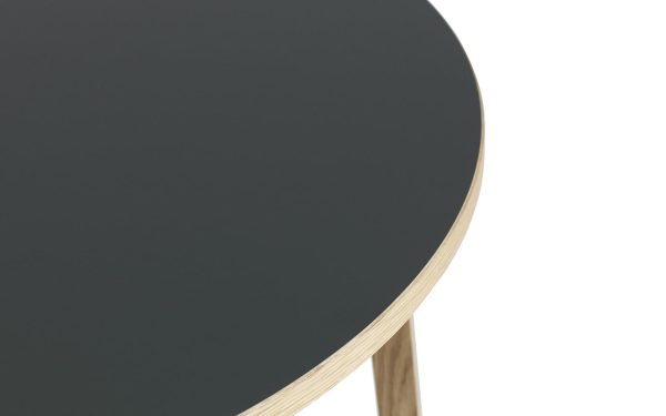 Et nærbillede af et rundt bord med en mørkegrå plade og en lys trækant, der fremhæver materialerne og rene TomorrowsDesign-detaljer.
