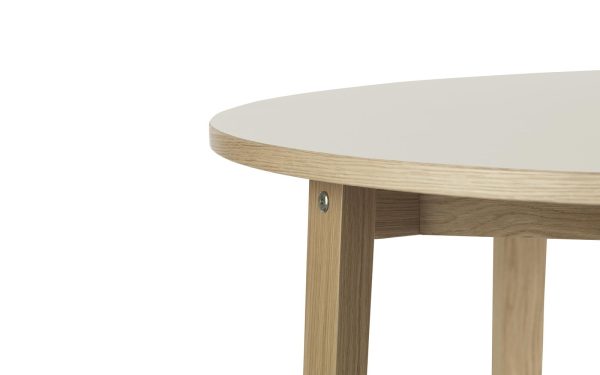 Nærbillede af hjørnet af et moderne bord med en glat, hvid plade og træben, der viser detaljerne i snedker- og designmaterialerne.