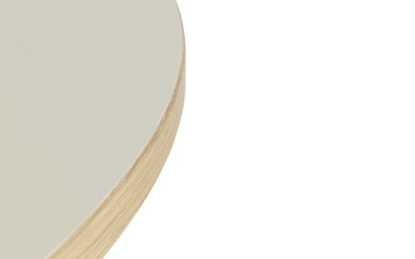 Nærbillede af en rund, beige overflade med en trækant, fokuseret på overgangen, hvor den glatte top møder den teksturerede side af dette interiørdesign.