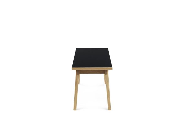 Et enkelt moderne designbord med en sort firkantet plade og lyse træben, isoleret på en hvid baggrund.