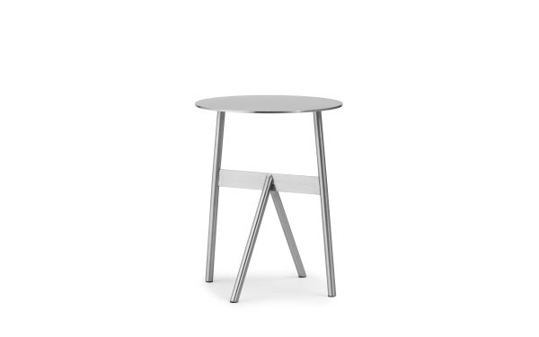 En moderne, minimalistisk skammel med et NORMANN COPENHAGEN - Stock Bord Ø37 cirkulært sæde og tre tynde, let spredte metalben, vist mod en skarp hvid baggrund.