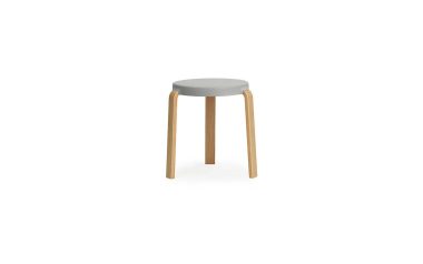 En enkel skammel med et rundt, gråt sæde og tre lyse træben, isoleret på en hvid baggrund. NORMANN COPENHAGEN - Tap Skammel