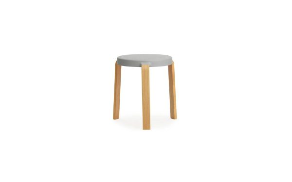 En enkel, moderne Normann Copenhagen - Tap Skammel skammel med et rundt, gråt sæde og tre lyse træben på hvid baggrund.