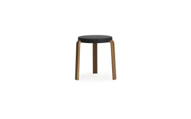 A NORMANN COPENHAGEN - Tap Skammel med en sort rund pude og tre lysebrune træben, stående mod en hvid baggrund.