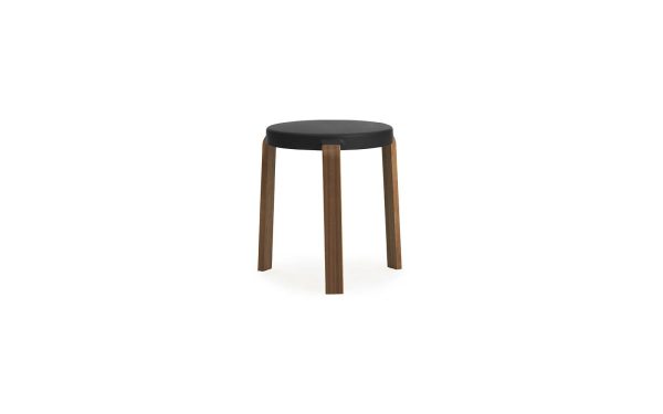 En enkel rund NORMANN COPENHAGEN - Tap Skammel med sort sæde og tre ben, isoleret på en hvid baggrund.