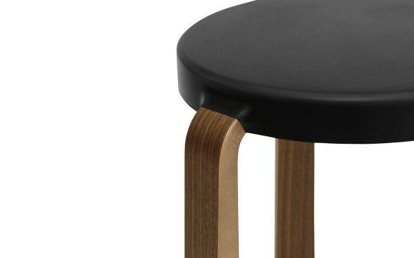 Nærbillede af en NORMANN COPENHAGEN - Tap Skammel med et sort rundt sæde og buede træben med en let finish, isoleret på en hvid baggrund, der afspejler essensen af TomorrowsDesign.