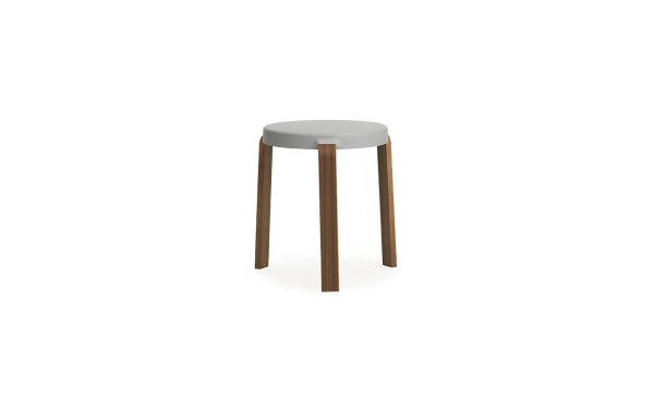 En moderne skammel med et rundt, lysegråt sæde og tre mørkebrune træben, isoleret på hvid baggrund af NORMANN COPENHAGEN - Tap Skammel.