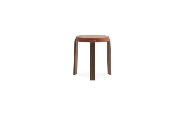 En simpel Normann Copenhagen - Tap Skammel med et rundt, fladt brunt sæde og tre slanke ben, isoleret på en hvid baggrund.