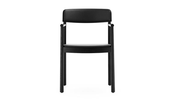 En sort, moderne stol med et enkelt design, med polstret ryglæn og sæde med træben, isoleret på en hvid baggrund - NORMANN COPENHAGEN - Timb Spisebordsstol.