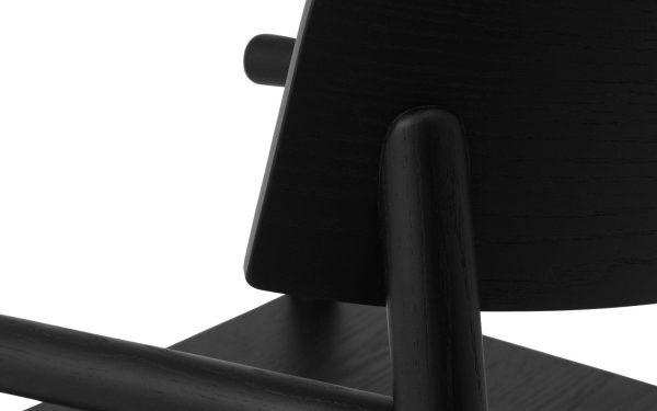 Nærbillede af en sort træstol med fokus på armlæn og ryglæn, der viser TomorrowsDesign detaljer med glatte, rene linjer. Billedet præsenterer et monokromatisk farveskema og minimalistisk æstetik.